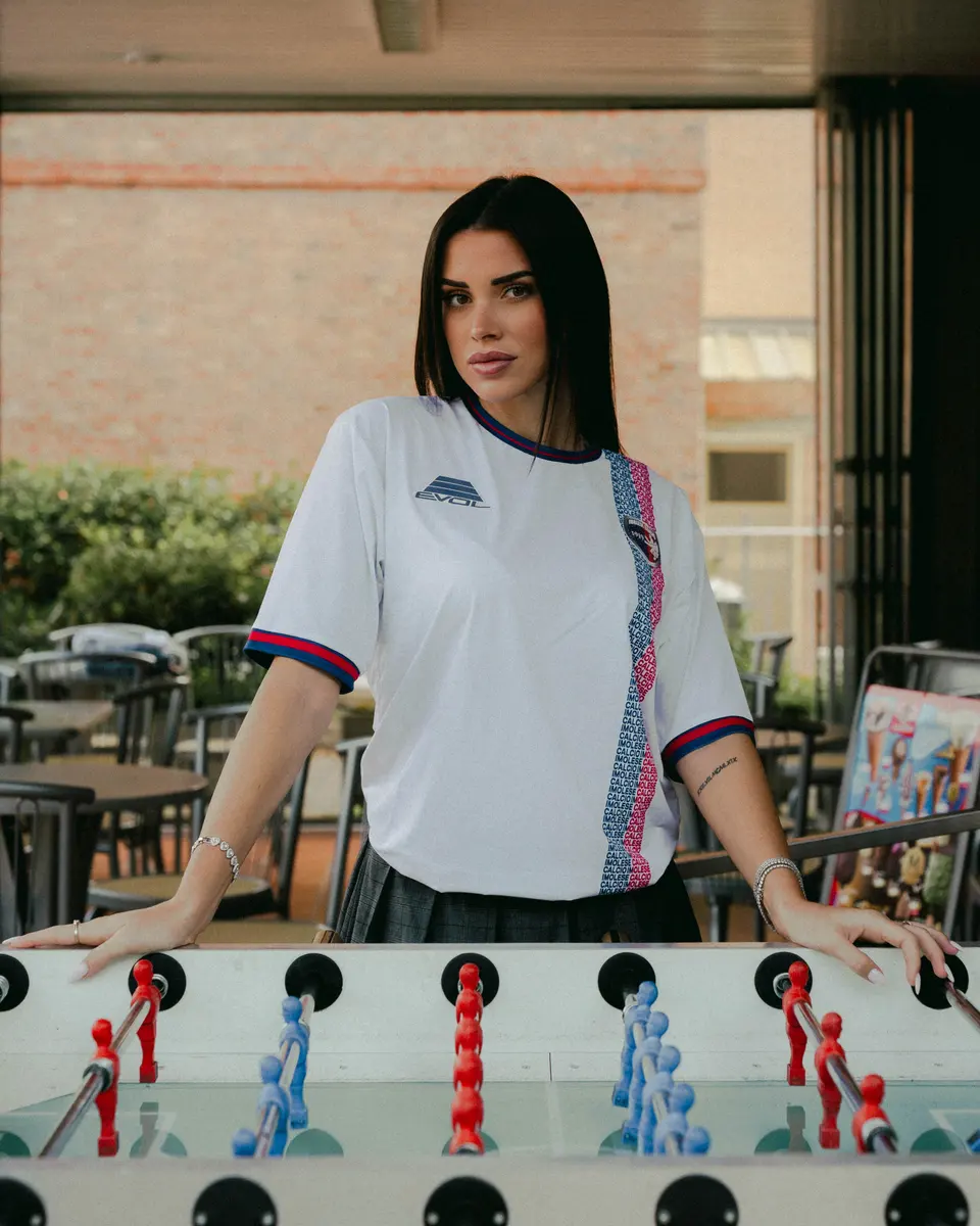 Una ragazza con la maglia bianca 2026/27 dell’Imolese davanti a un biliardino