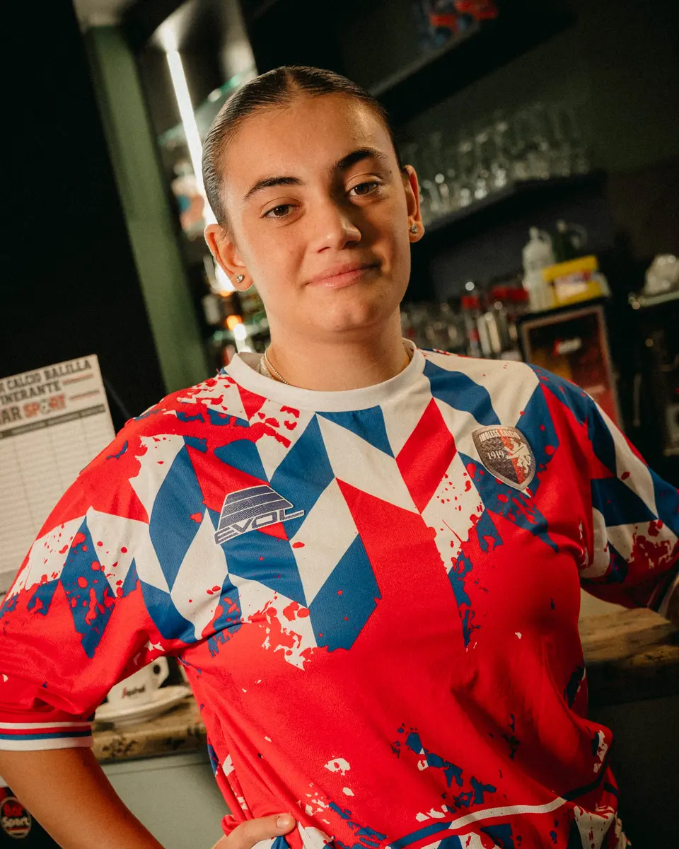 Una ragazza con la maglia rossa 2026/27 dell’Imolese al bancone del bar