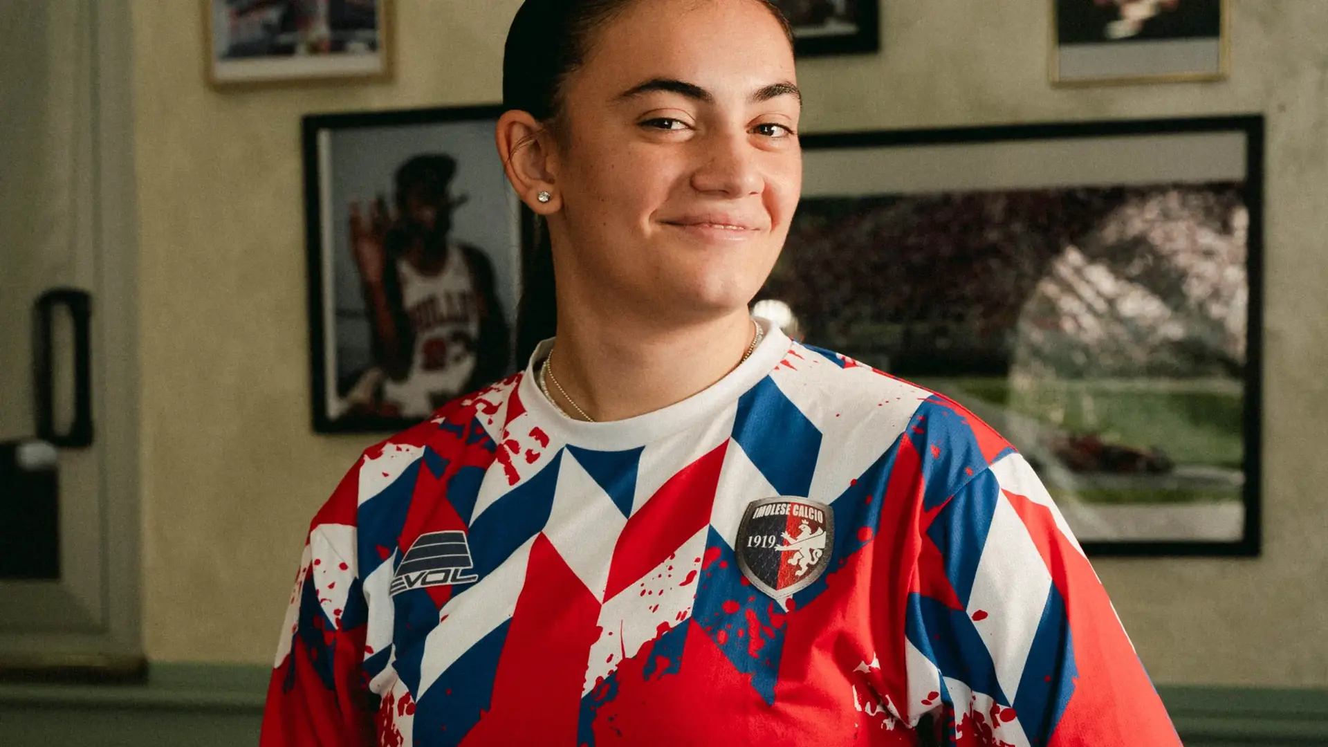 Una ragazza sorridente con la maglia rossa 2026/27 dell’Imolese