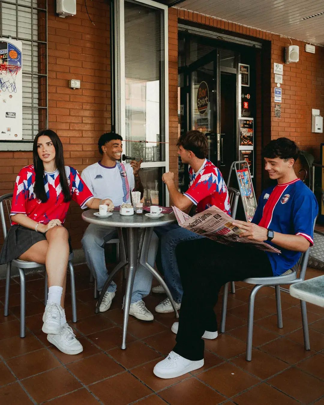 Quattro ragazzi con le maglie 2026/27 dell’Imolese seduti al tavolino all’aperto di un bar